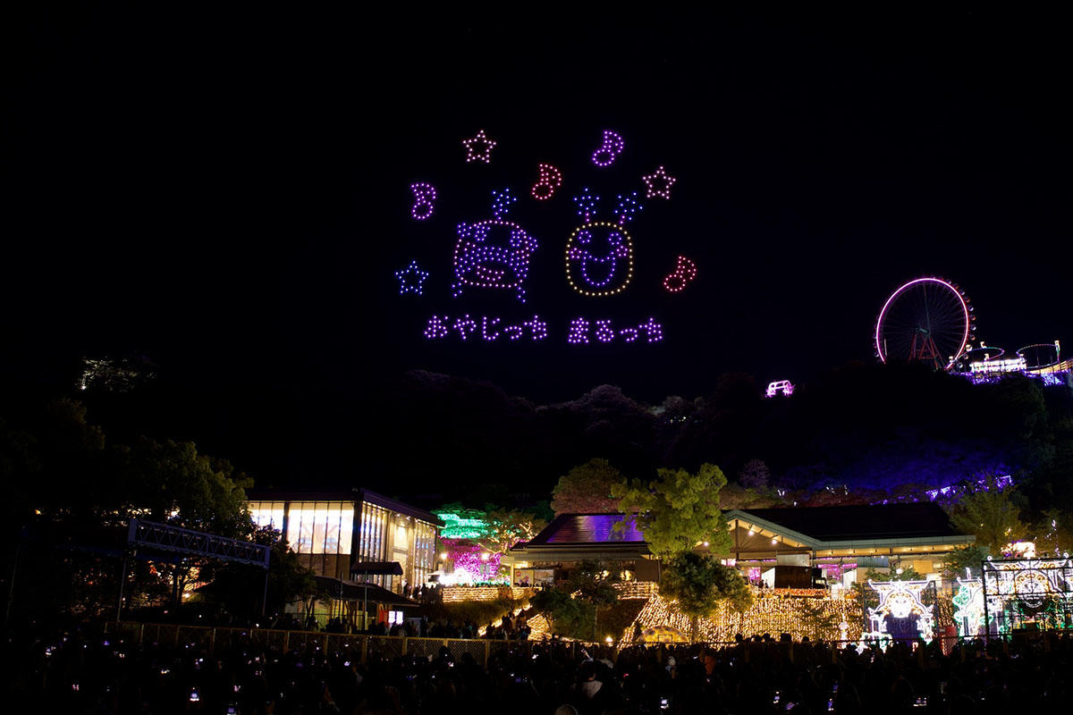 おやじっちとまるっちが音符や星とともに夜空に描かれたドローンショーのシーン