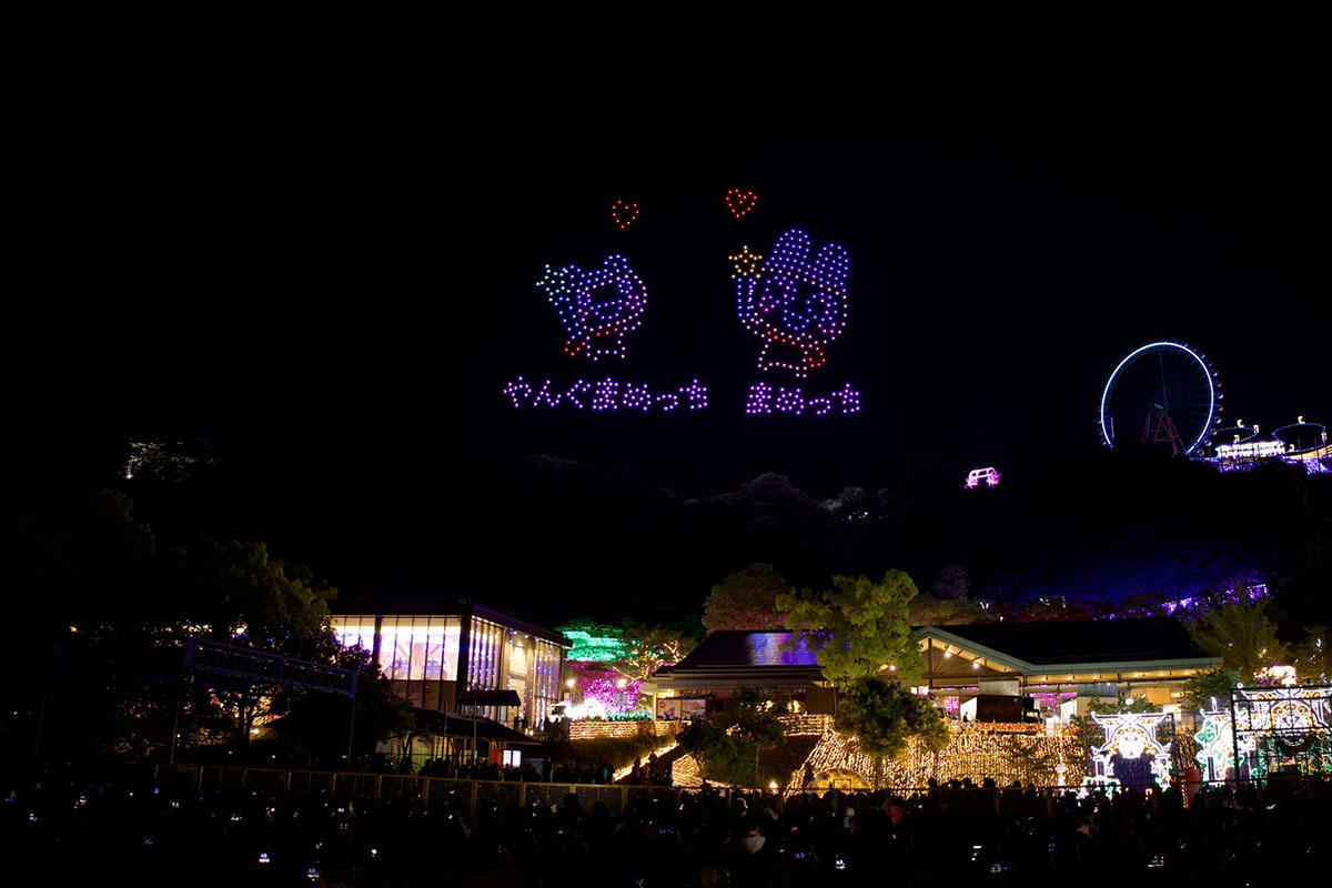 やんぐまめっちとまめっちがハートとともに夜空に描かれたドローンショーのシーン
