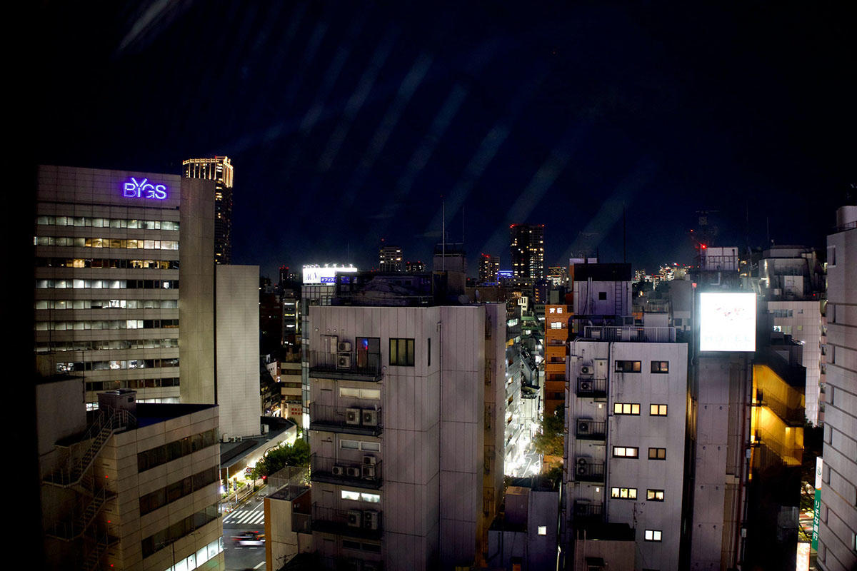 1109号室の窓から見た新宿三丁目のビルと夜の街